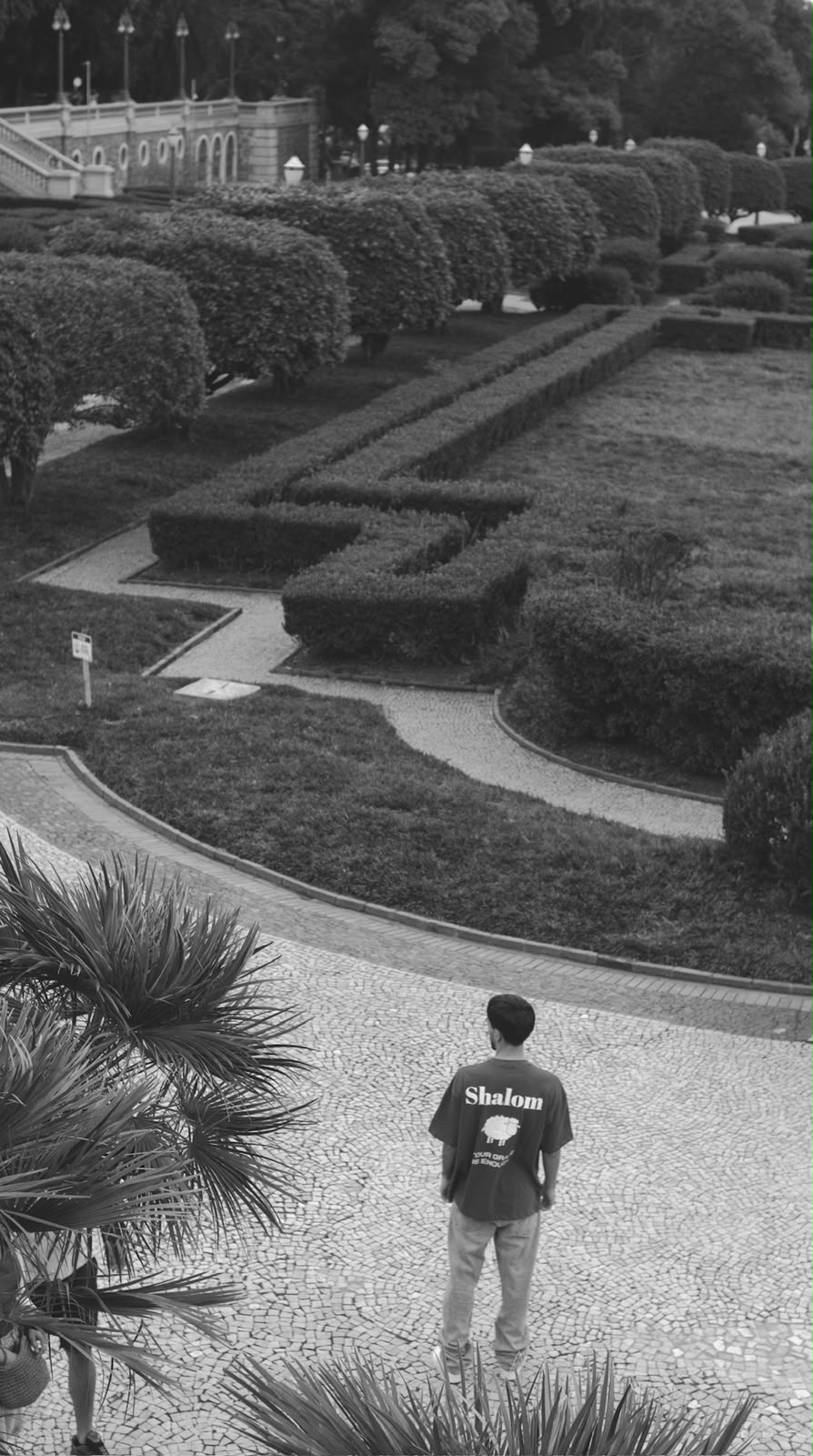 Homem em jardim clássico usando camiseta preta SHALOM Your Grace Is Enough — foto preto e branco