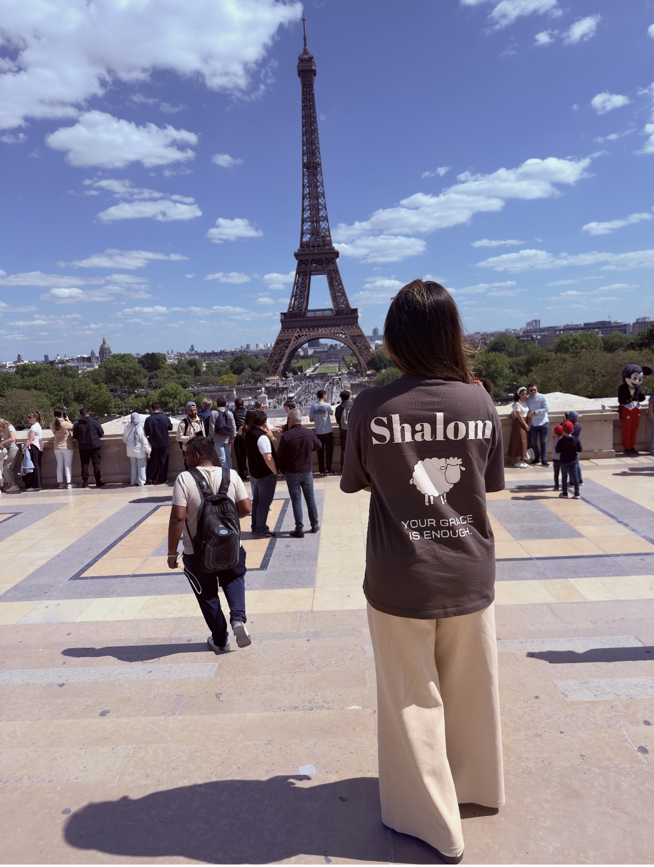 Mulher no Trocadéro com camiseta marrom SHALOM e Torre Eiffel ao fundo